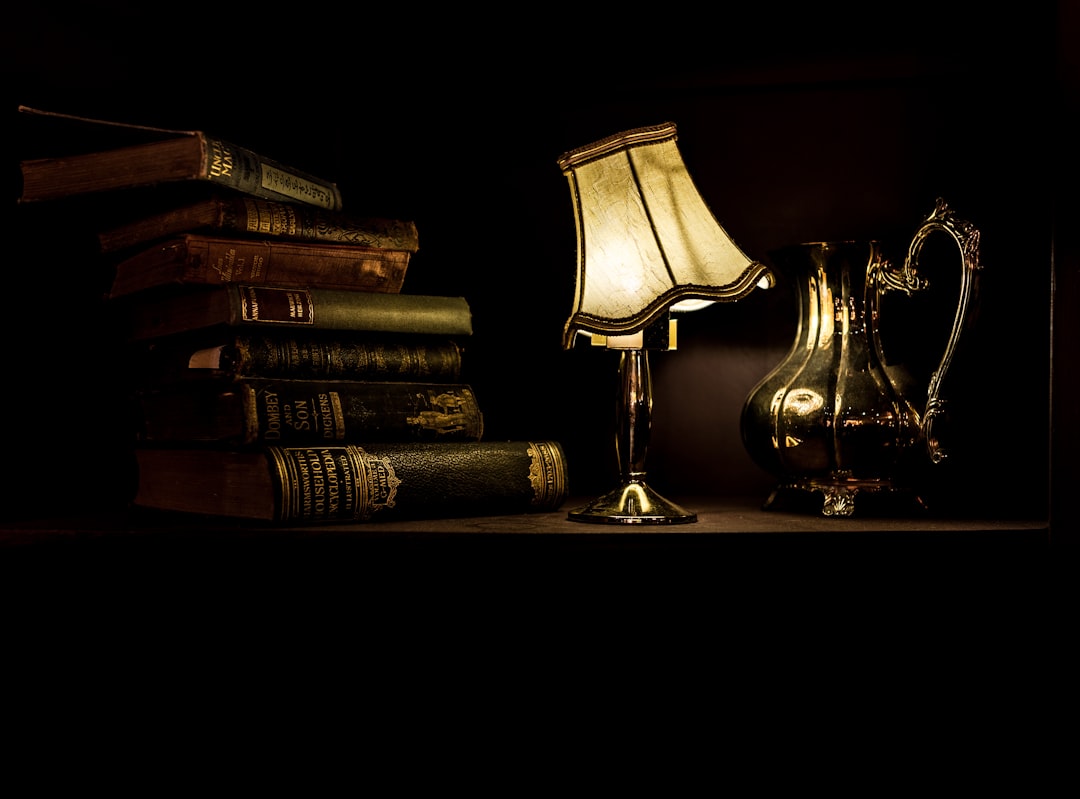 turned on desk lamp beside pile of books turned on desk lamp beside pile of books