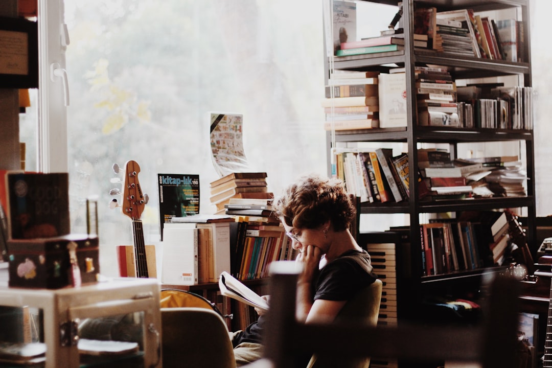woman reading book sitting beside electronic keyboard woman reading book sitting beside electronic keyboard