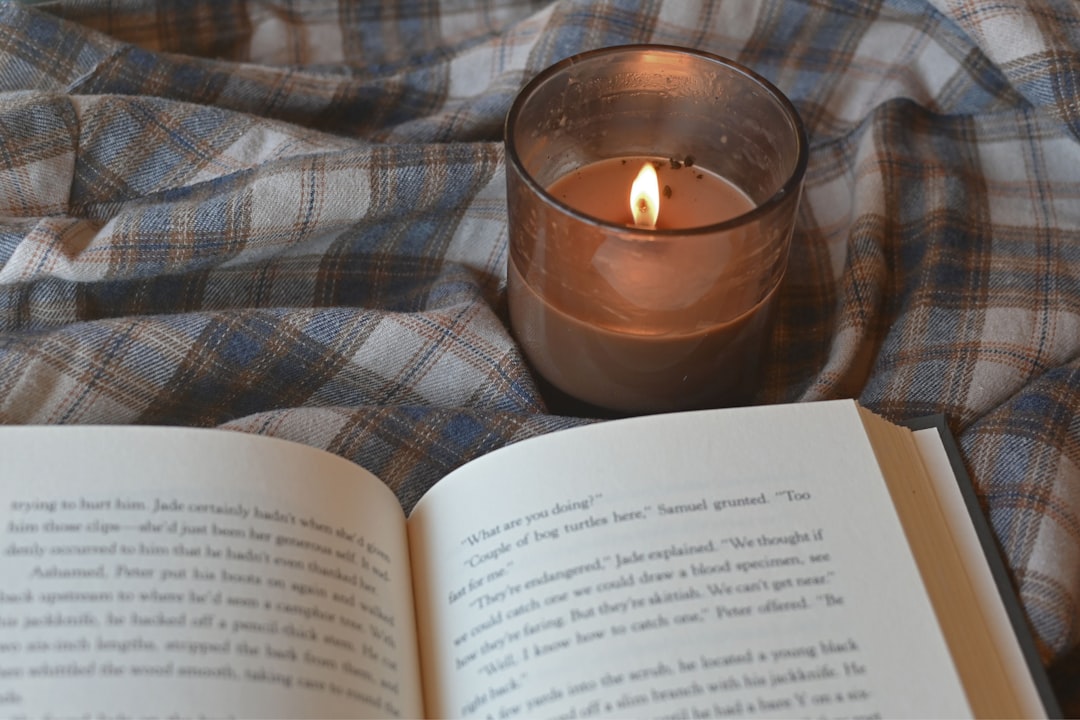 an open book and a lit candle on a blanket an open book and a lit candle on a blanket