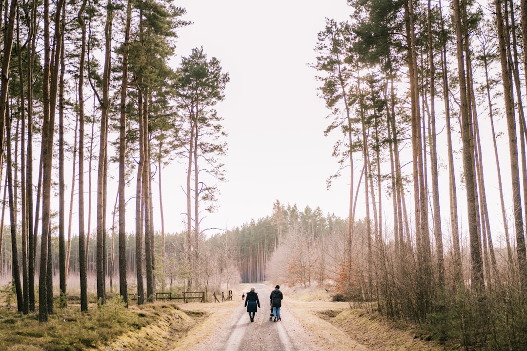 two people walking down a dirt road in the woods two people walking down a dirt road in the woods