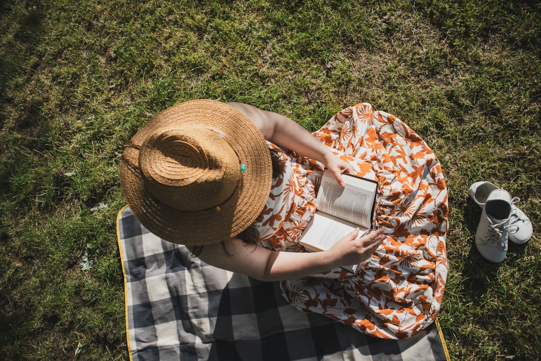 A woman sitting on a blanket on top of a field